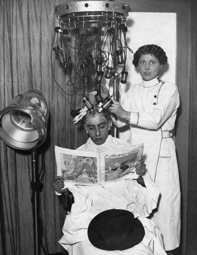 1935 г. Косметолог прикрепляет к голове мужчины трубки и подушечки машины для лечения волос. девушки, мода, фен