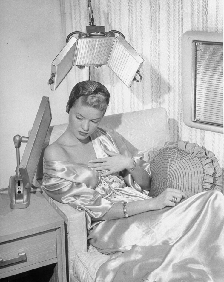 1948 г. Женщина использует тепловой светильник и фен из стекла. девушки, мода, фен