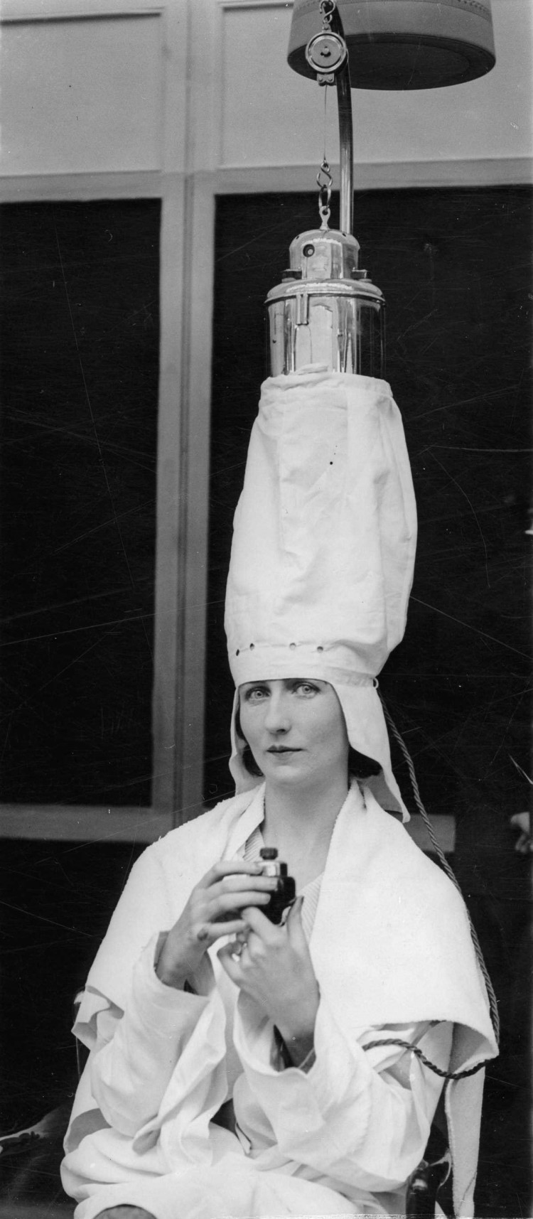 1930 г. Женщина демонстрирует аппарат для обработки волос паром на парикмахерской выставке в Лондоне. девушки, мода, фен