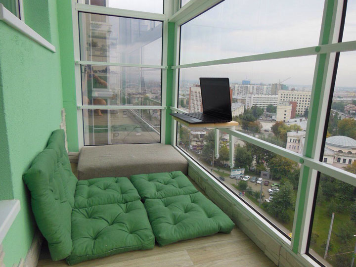 Зеленые подушки вместо кровати на панорамном балконе