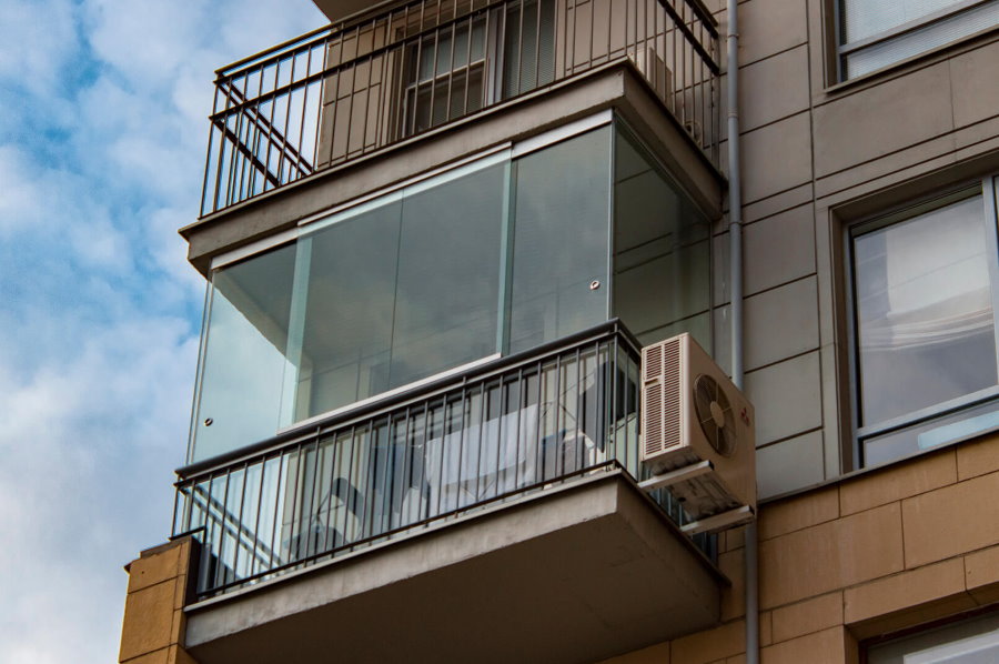 Вид снаружи на балкон с безрамным остеклением