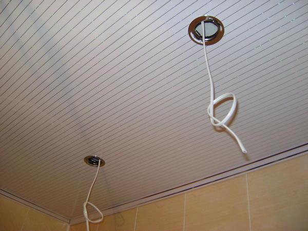 Заключительный этап обустройства потолочных перекрытий в ванной комнате - монтаж осветительных приборов в пластиковых панелях