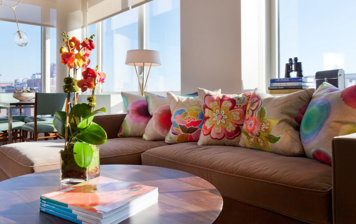 Подушки с цветами на диване коричневого окраса