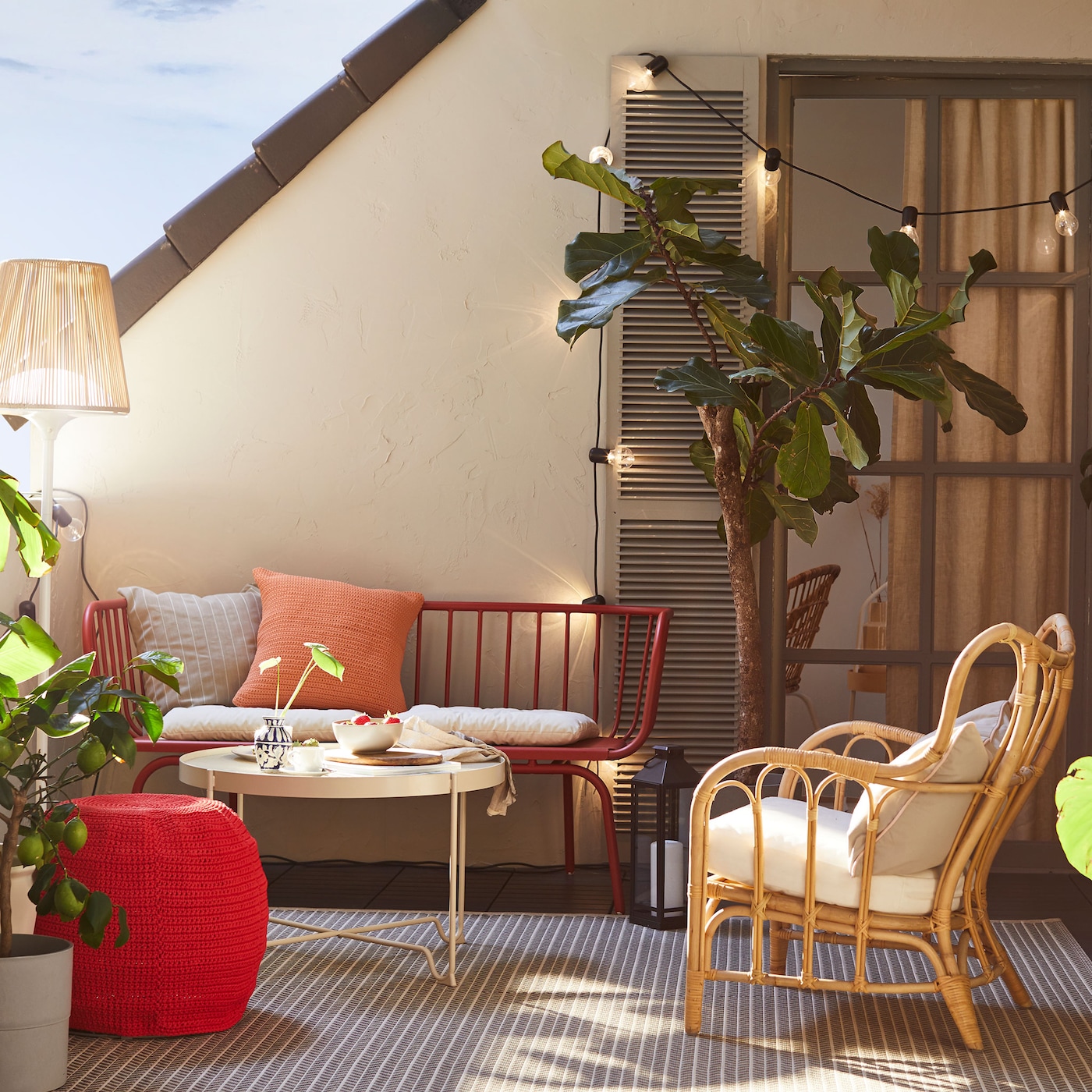Balcony scene with HAVSTEN in/outdoor sofa and lots of cushions, surrounded by plants.