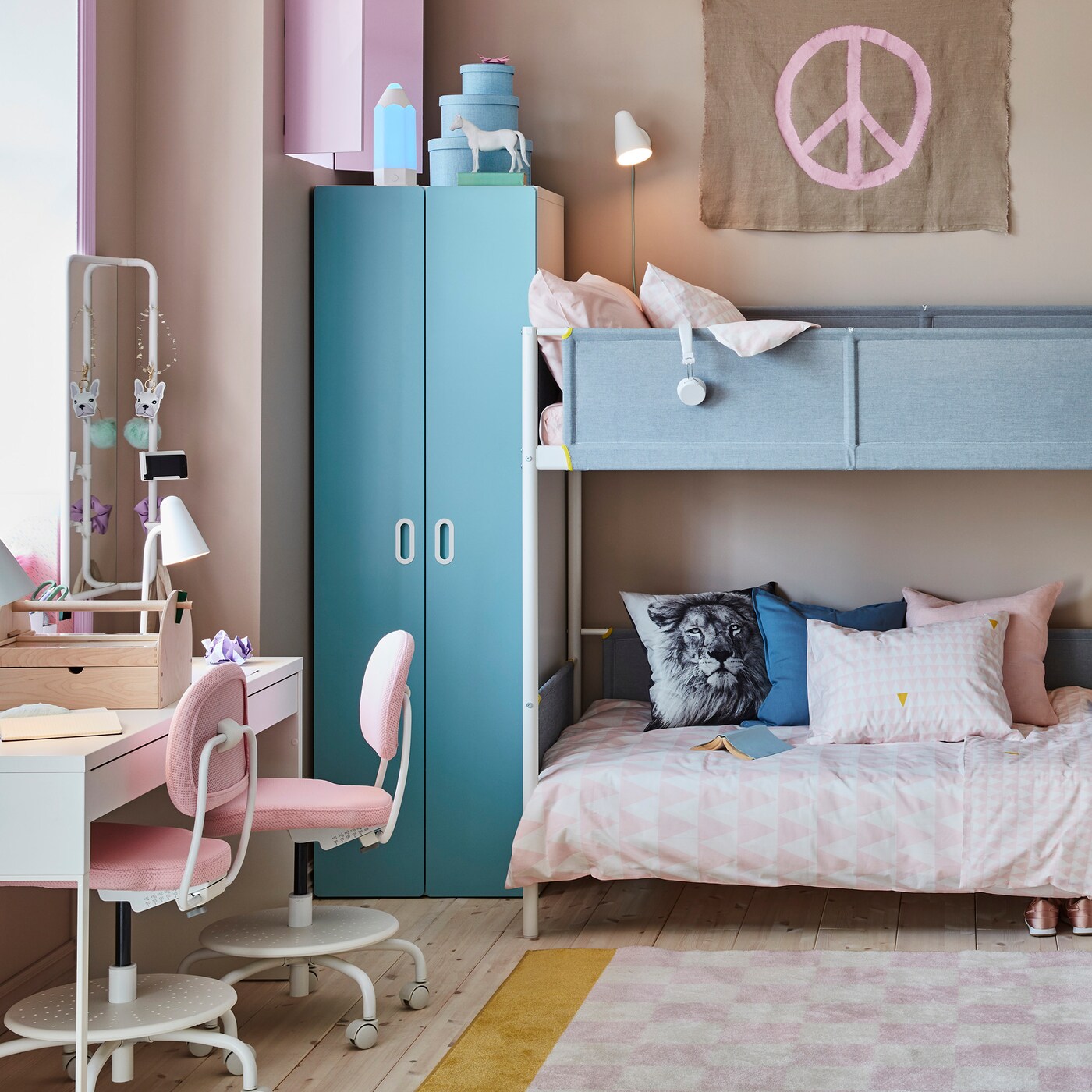 Children’s room with a bunk bed with bedding and pillows, a closet beside it, a chest of drawers and a desk and chairs.